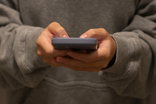 Closeup of a teenager using a mobile phone. Social media apps, screen time, short video streaming, and video games concepts.