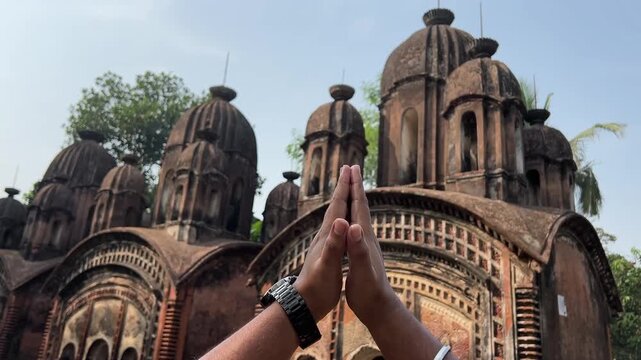 Hands of a Hindu man, praying in front of a old ruin temple in Bengal
