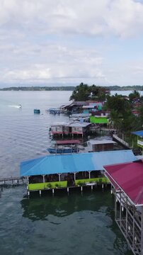 Vertical aerial view showcasing coastal houses on stilts over serene waters on Bastimentos Island in Bocas Del Toro, Panama.