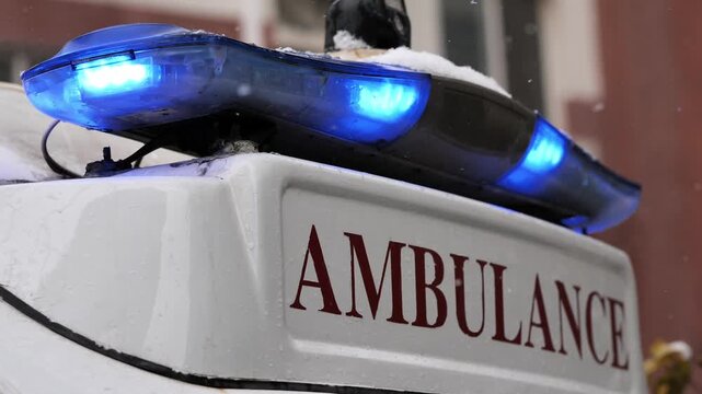Ambulance with flashing blue lights on a snowy day, symbolizing urgent rescue in harsh weather.