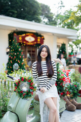 A young woman is decorating a Christmas tree with ornaments, getting ready for the winter holiday season. It's a celebratory scene in front of the house.