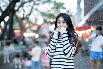  A young woman wearing a scarf and gloves is smiling outdoors in the snow during the winter.
