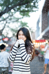  A young woman wearing a scarf and gloves is smiling outdoors in the snow during the winter.