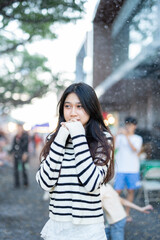  A young woman wearing a scarf and gloves is smiling outdoors in the snow during the winter.