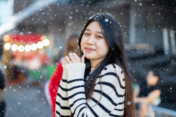  A young woman wearing a scarf and gloves is smiling outdoors in the snow during the winter.