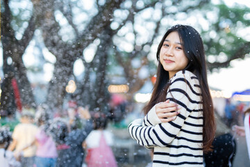  A young woman wearing a scarf and gloves is smiling outdoors in the snow during the winter.
