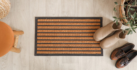 Door mat with shoes on floor in hallway, top view