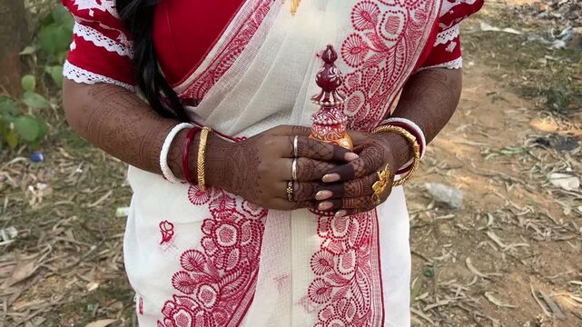 A Bengali bride holding a sindur box in red and white saree for wedding in India 