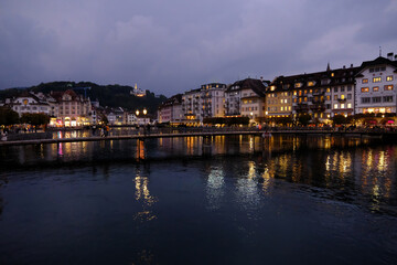 Obraz premium Dusk view of Lucerne Reuss River with architectural reflections and pedestrians