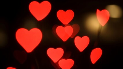 Glowing Red Hearts Scattered Across Dark Background with Dreamy Bokeh Effect