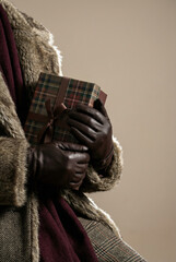 Hands in Leather Gloves Holding a Plaid Gift Box
