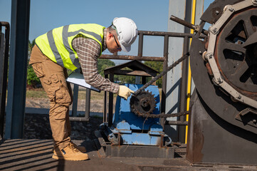 Engineer Inspecting Industrial Machinery During Routine Maintenance at Outdoor Facility