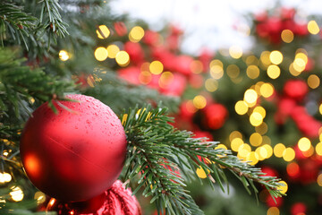 Christmas tree with red toy balls and festive illumination, golden lights on background. New Year tree with toys