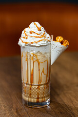 Caramel Swirl Milkshake With Whipped Cream In Glass, Caramel Drizzle And Pastry On Side