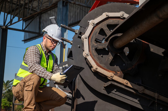 Industrial Worker Performing Equipment Inspection with Safety Gear at Outdoor Facility