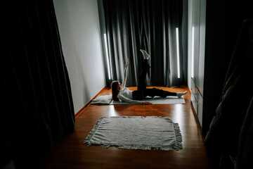 Young woman exercising at home on a mat in a dim room with soft lighting