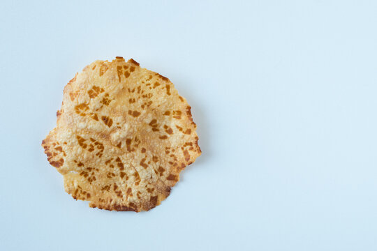 A crispy, golden-brown cracker "kerupuk jengkol" (Padang-style fried jengkol cracker) on a clean white background. Unique texture and mixed light and dark brown tones, is perfect for food and culture.