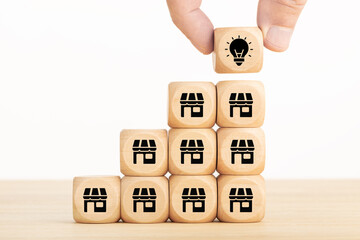 Store and franchise expansion concept to increase sales volume, man holds cube with light icon symbol on many stores icon; copy space. For business development and strategy to increase sales growth .