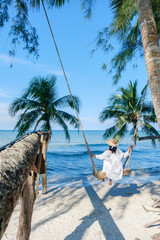 Relaxing on a swing by the beach under palm trees in Koh Kood, Thailand