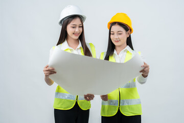 Two Asian female engineers review digital blueprints on a tablet, representing smart construction planning, professional teamwork, and how technology supports business growth inside a modern company.