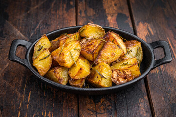Baked potatoes with rosemary and garlic in cast iron pan. Simple rustic vegetable side dish overhead view