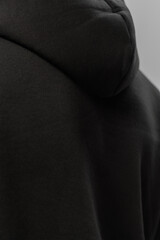 Close-up view of a person wearing a black hoodie in a simple setting during the daytime
