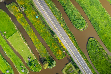 Aerial view of road passing through pattern of wetlands and canals in the Netherlands countryside.