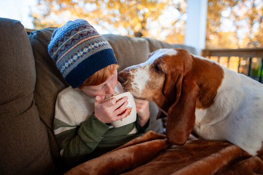 Autumn family moment child cuddled blanket sharing drink with dog