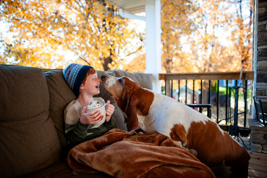 Boy and dog touch noses on warm autumn day