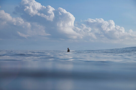 one Surfer On Calm Sea Sitting On Surfboard Near Horizon