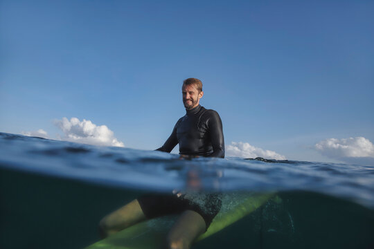 Man Surfer Sitting On Surfboard, Split Shot