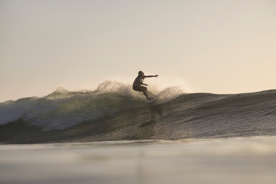 Surfer Tucked Inside Translucent Barrel at sunset
