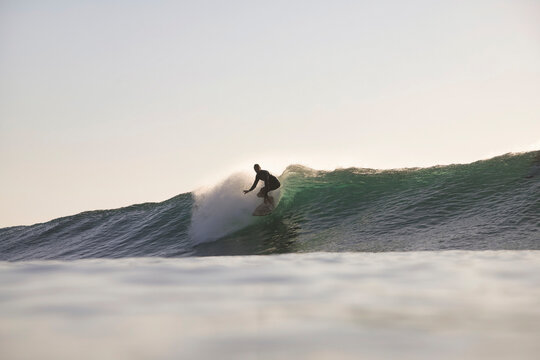 Surfer Tucked Inside Translucent Barrel at sunset