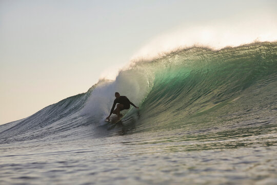 Surfer Tucked Inside Translucent Barrel at sunset