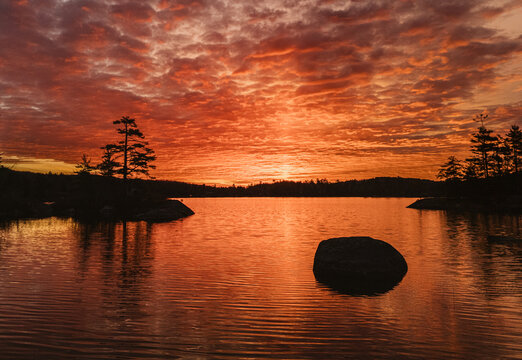 Incredible sunrise over peaceful lake with pine trees, Maine