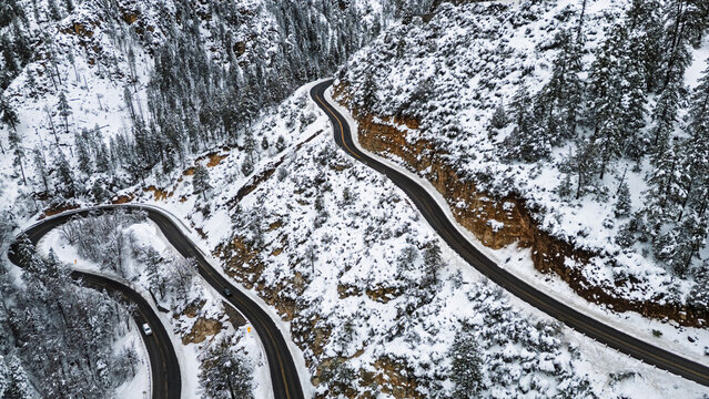 Aerial view of two cars on a switchback, snow-covered Arizona highway