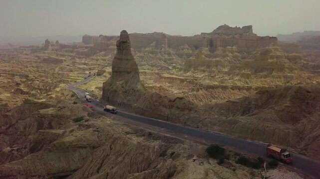Cinematic drone shot moving anticlockwise above of road and mountain in buzi pass top with trucks Makran coastal Highway Balochistan, Pakistan