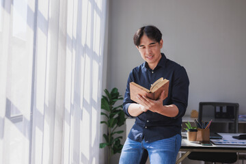 Fototapeta premium Asian man enjoying reading book in minimal room