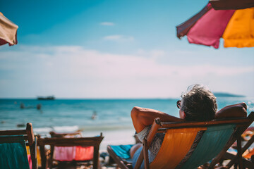 a man relaxes on the beach in lawn chairs under an umbrella