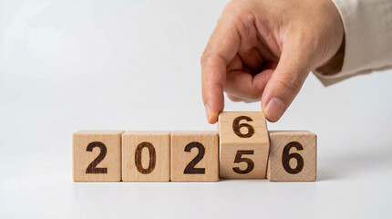 Hand changing wooden blocks from 2025 to 2026 symbolizing New Year transition, planning, and future goals