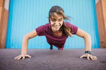 Young woman confidently doing fitness push-ups outdoors