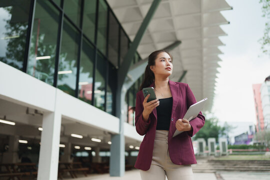 Young businesswoman standing with smartphone and tablet looking forward