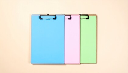 Three colorful clipboards, blue, pink, and green, arranged on a beige surface