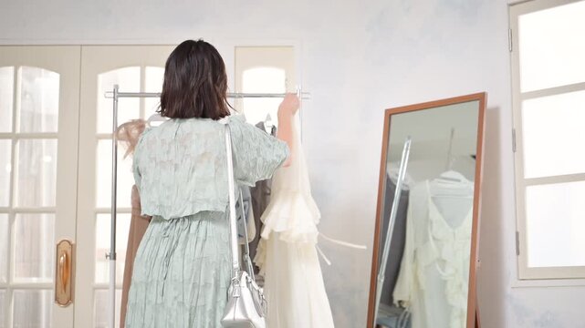 洋服を手に取り笑顔で選ぶ若い女性のガーリーファッションライフスタイルの顔無しの動画