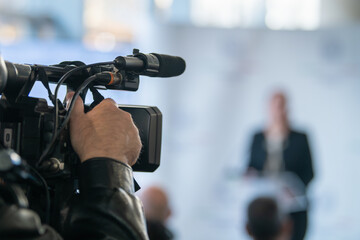 TV camera focused on podium during press briefing. Highlights communication accuracy, media presence, and organized public message delivery.