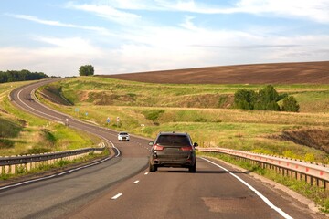 Fototapeta premium Passenger car on a picturesque country road in summer. Traveling by car.
