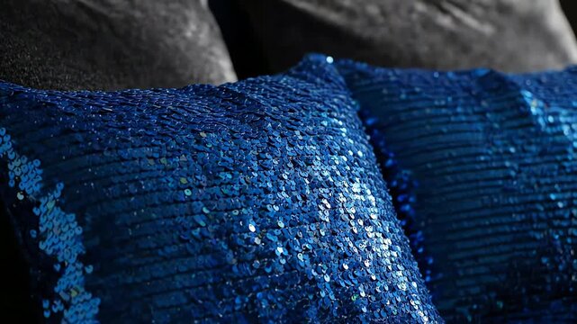 Close up shot of bright blue sequin throw pillows with shimmering texture and dark background