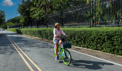 Asain Woman Cycling on a Pave Path in a Park