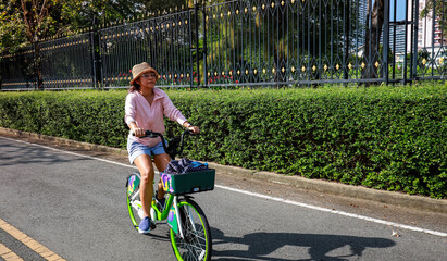Asain Woman Cycling on a Pave Path in a Park
