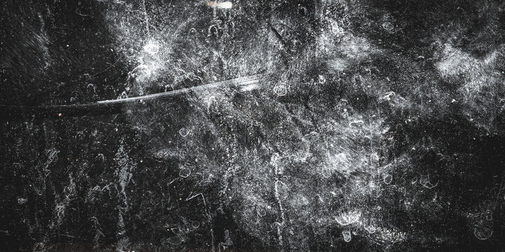 Abstract black grunge textured background with white scratches, stains, and dust effects. The rough, worn surface creates a dramatic, dark, and artistic impression.